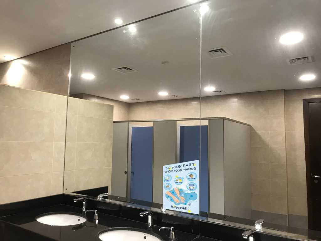 Big mirror image of toilet cubicles of an Men washroom and wash